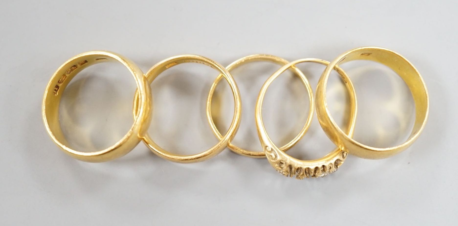 Four assorted mainly early 20th century 22ct gold wedding bands and an 18ct and diamond chip set ring(stones missing